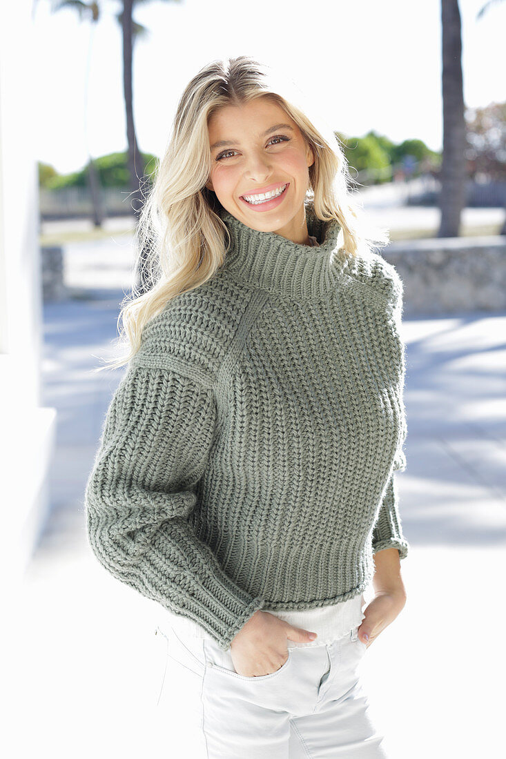 A young blonde woman wearing a grey knitted jumper