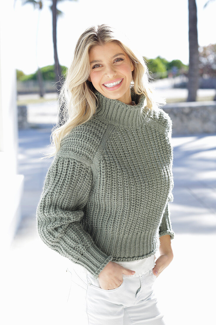 Junge blonde Frau in grauem Strickpullover