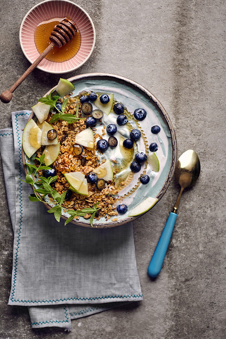 Frühstücksbowl mit Blaubeerjoghurt, Granola, Apfel und Minze