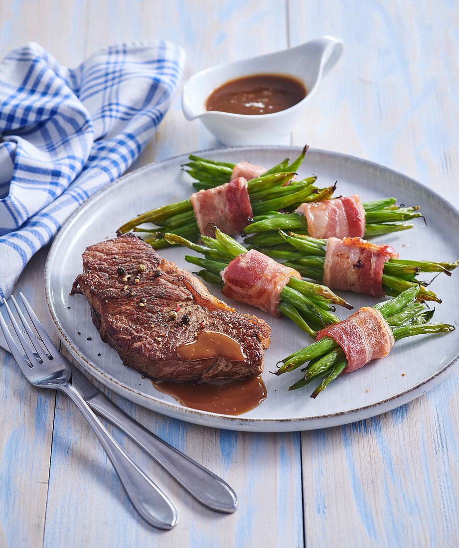 Beefsteak with green beans in striped bacon