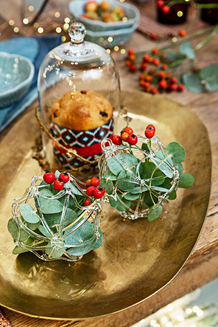 Weihnachtliche Tischdekoration mit Eukalyptus- und Beerenzweigen auf Goldteller
