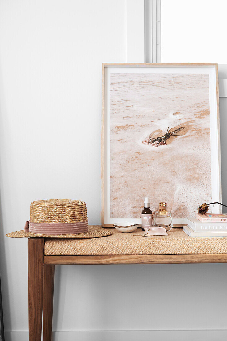 Straw hat, leaning picture and perfume bottle on bench