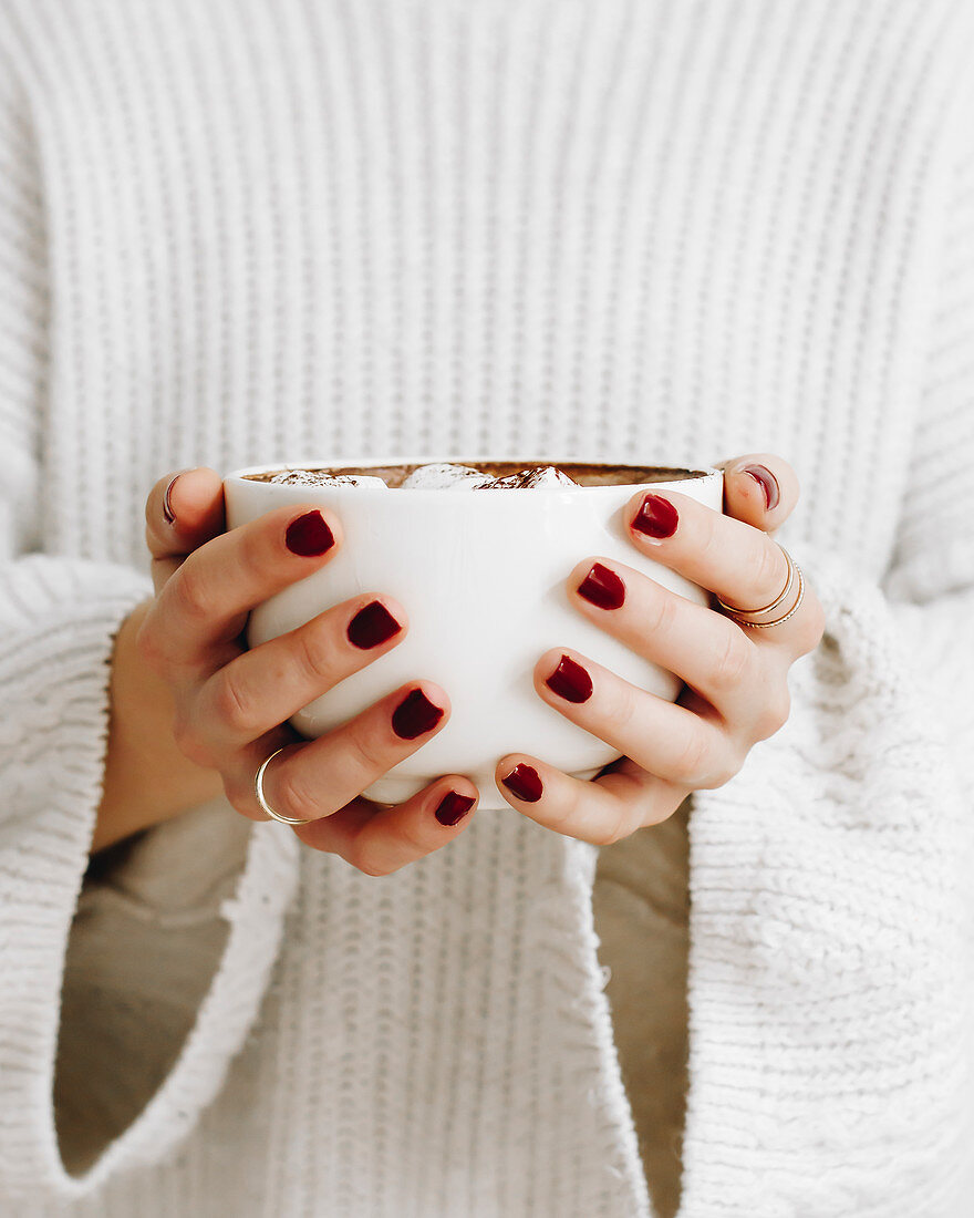 Woman holds a mug of hot chocolate with marshmallows