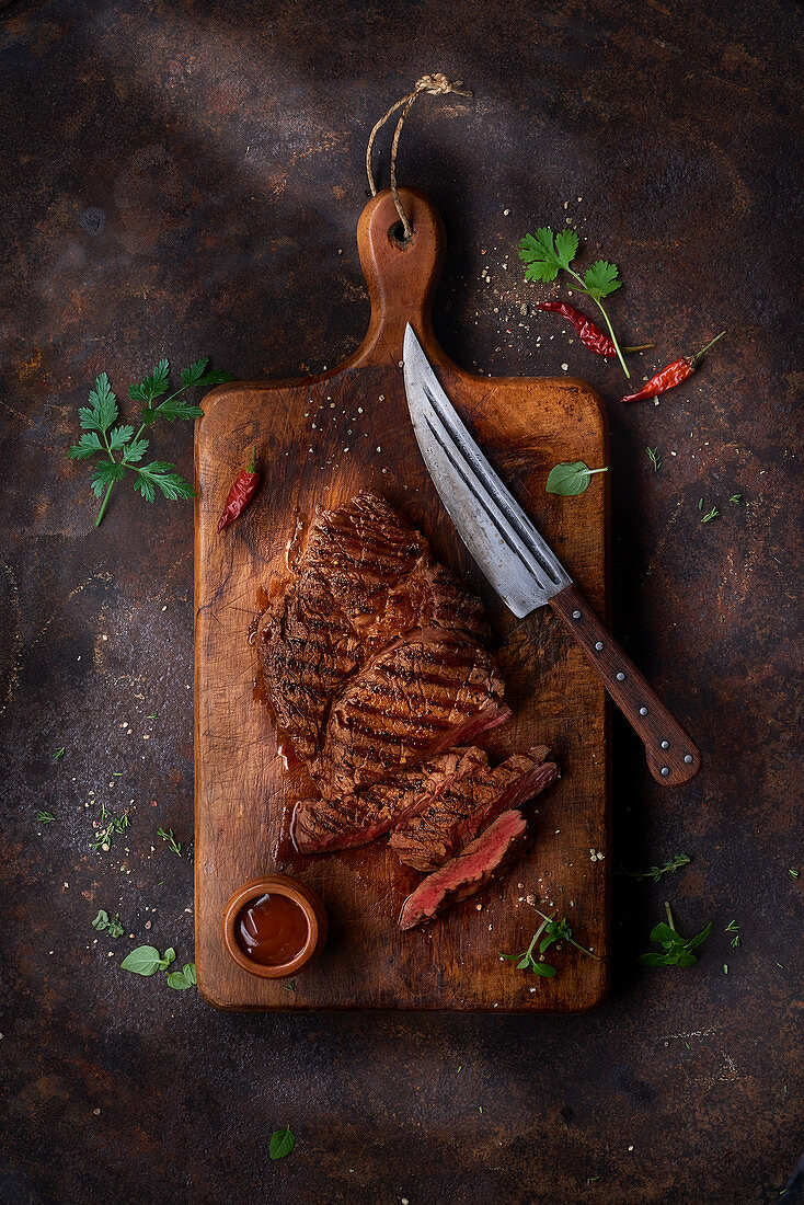 Grilled steak on a ceramic and wood board on marble table