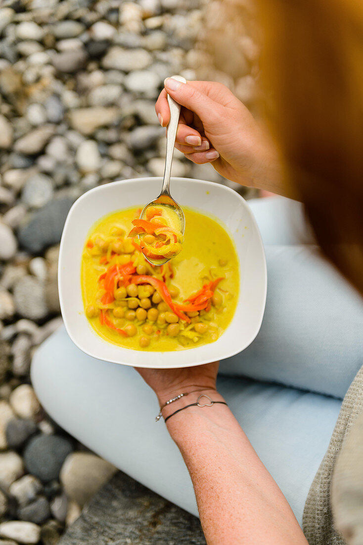 Frau löffelt Kichererbsen-Curry