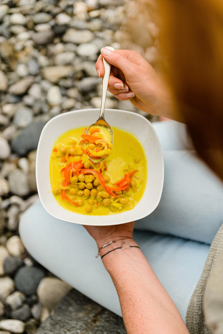 Woman eating chickpea curry with a spoon