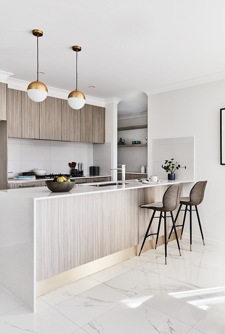 Modern, open-plan kitchen with pale grey cabinets and gold accents