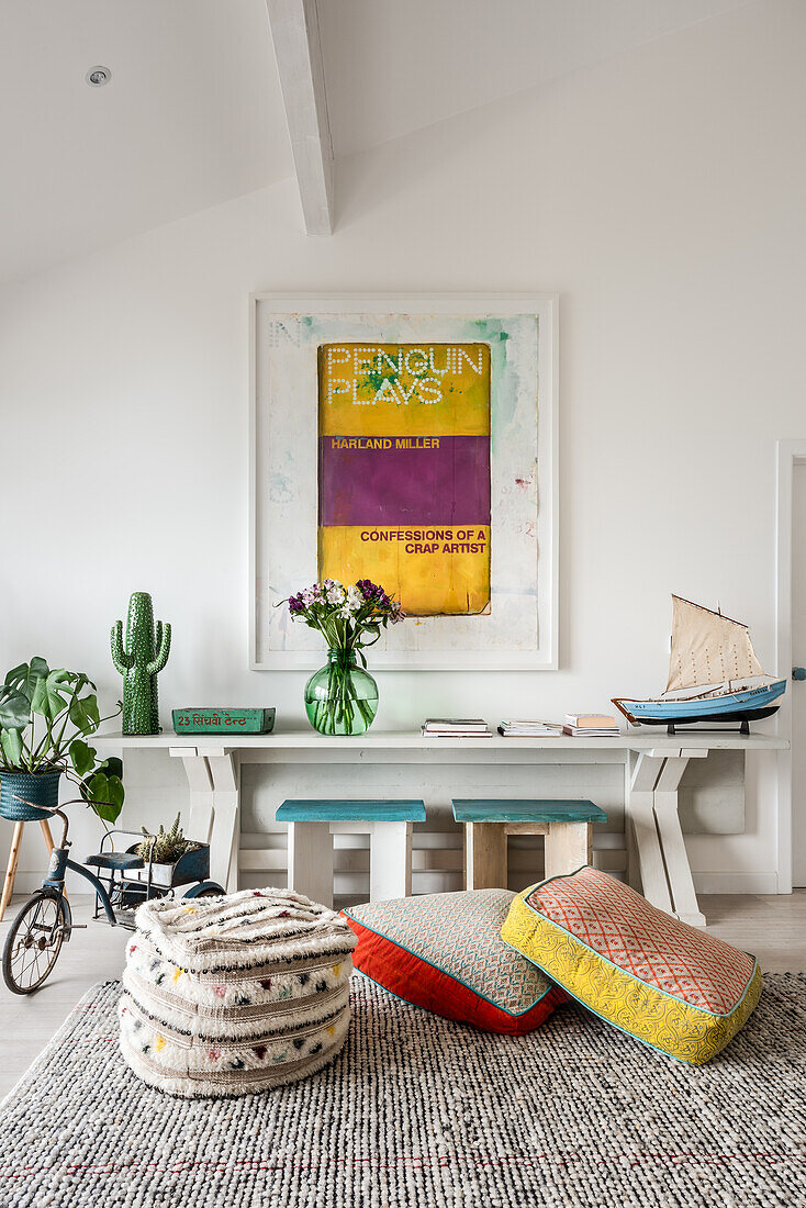 Framed art above console table with floor cushions