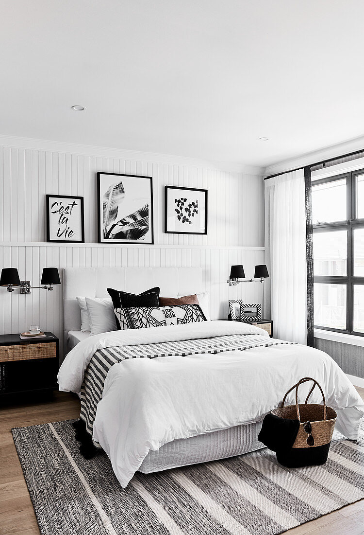 Artworks on picture ledge in monochrome bedroom