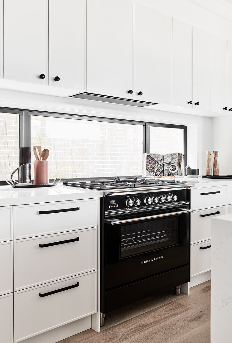 Gas cooker in classic, white kitchen with horizontal window