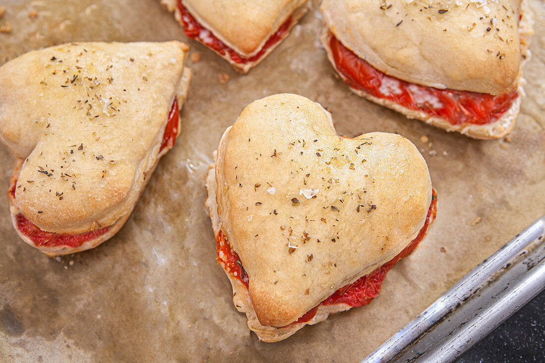 Herzförmige Pizzateig-Sandwiches mit Tomaten, Mozzarella und Basilikum