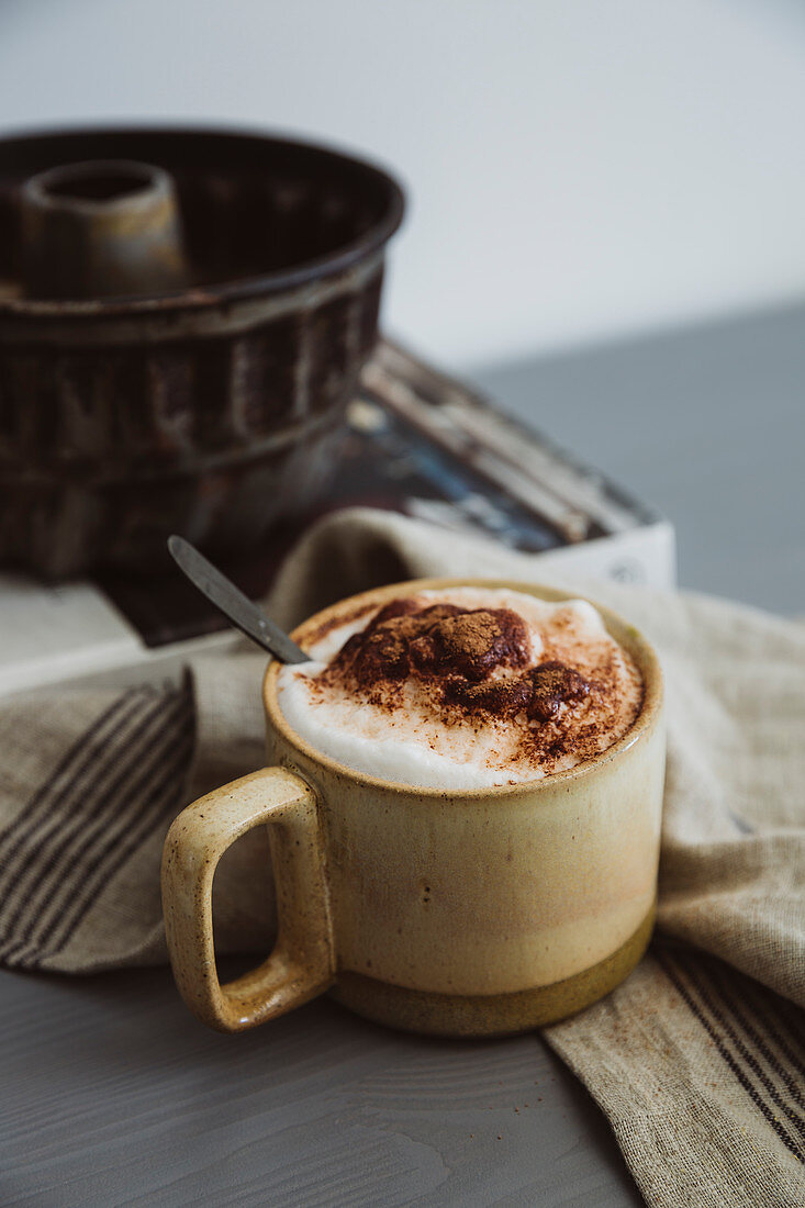 Cappuccino mit Milchschaum und Kakopulver in Keramiktasse