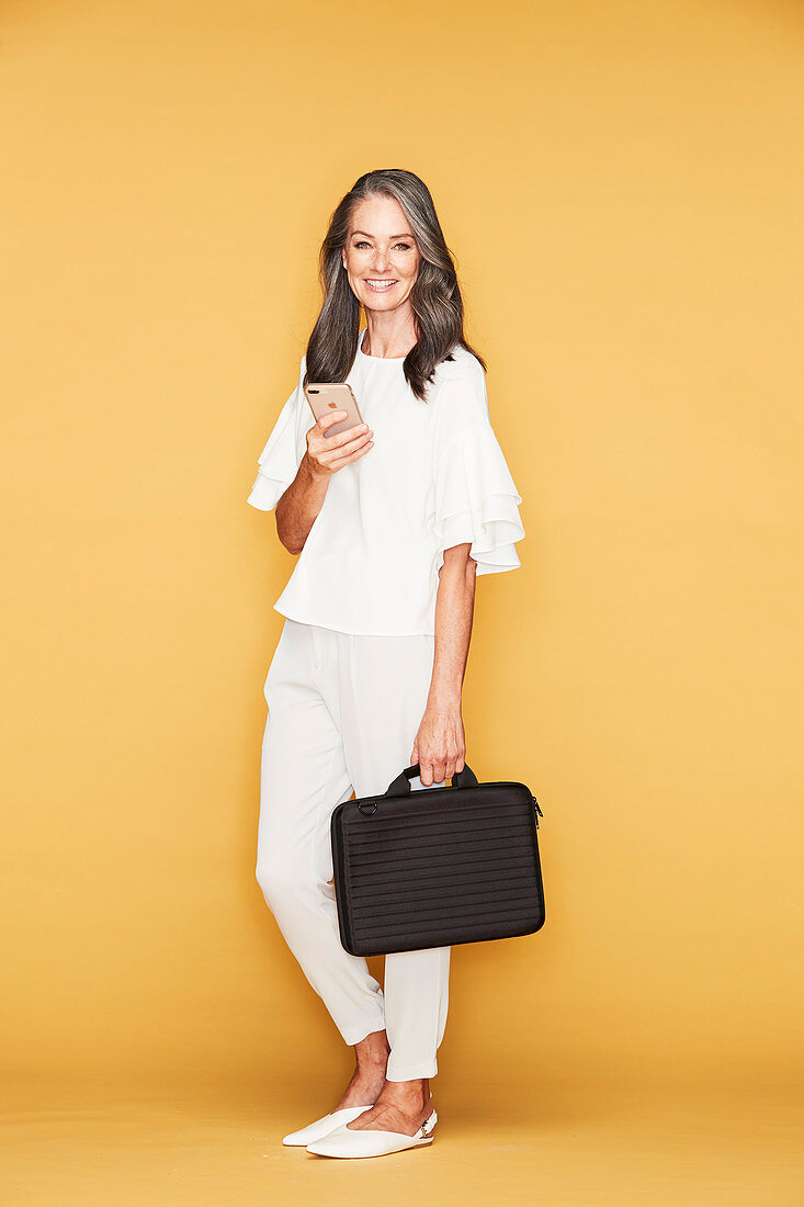 Frau in weißer Bluse und Hose, mit schwarzer Notebook-Tasche