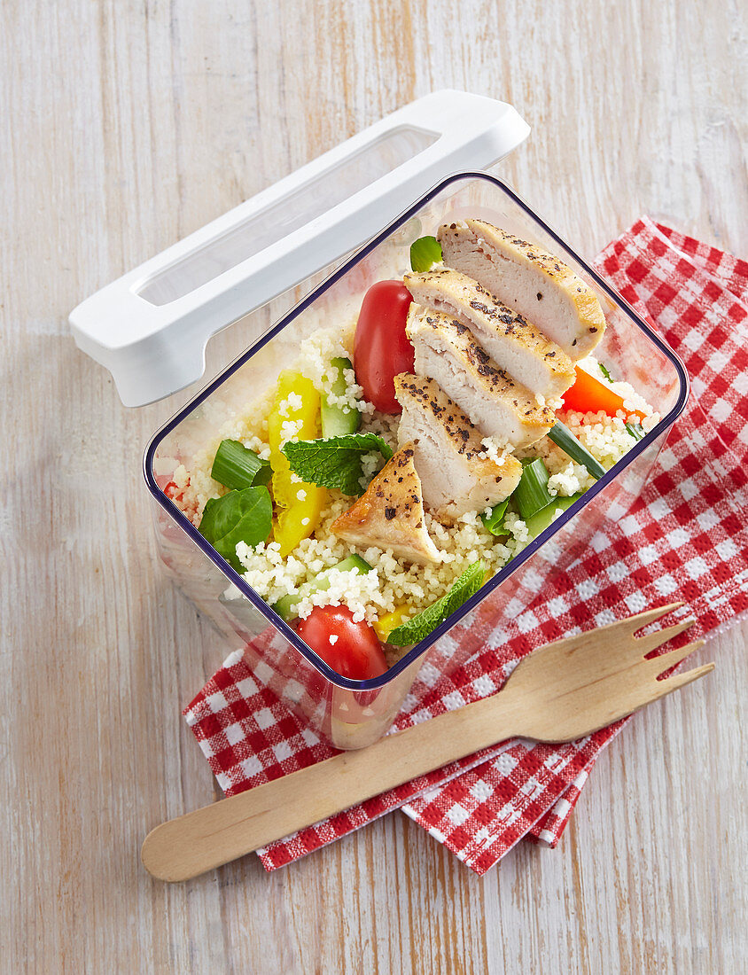 Couscous mit Hühnerbrust und Gemüse in Lunchbox zum Mitnehmen