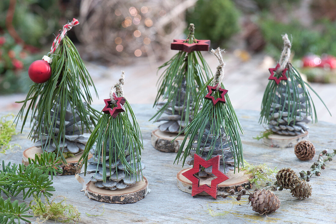 Small trees made of pinecones, pine branches, and wooden discs decorated with wooden stars and red ornaments