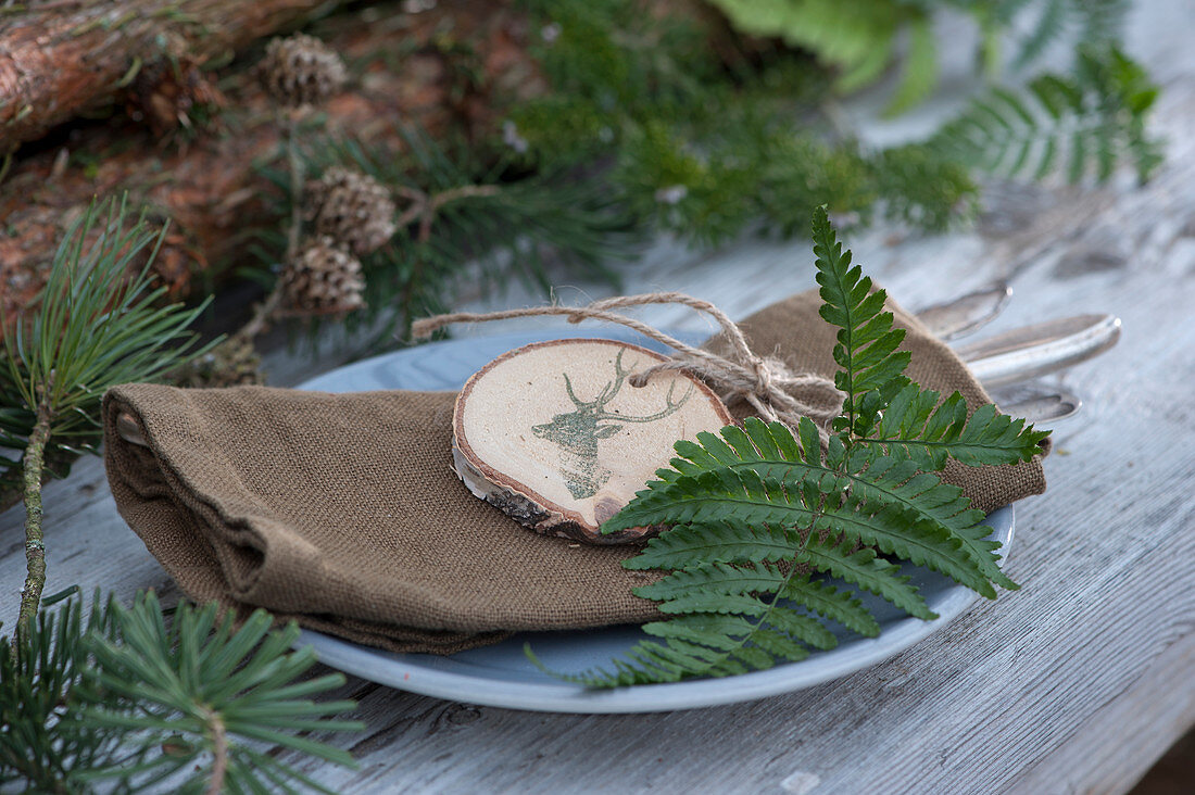 Homemade pendant made from a wooden disc with a fern leaf as a napkin decoration