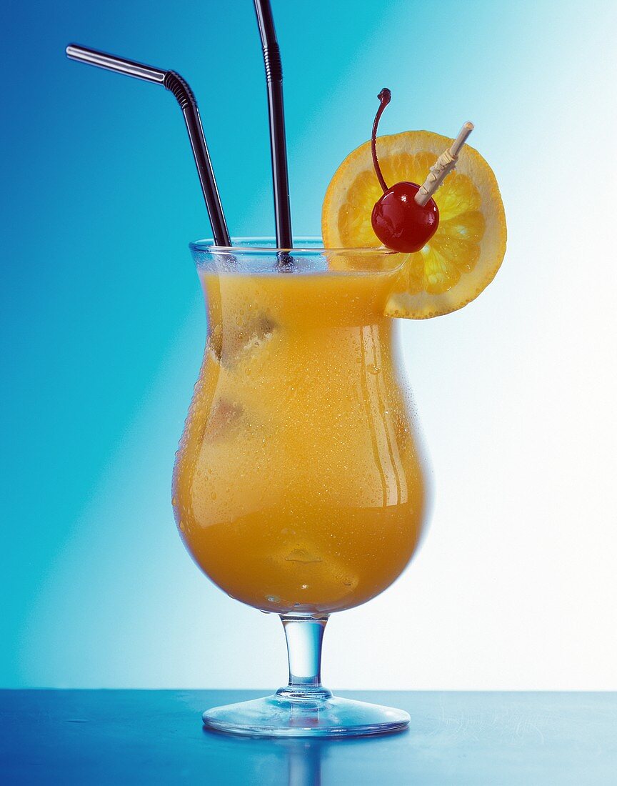 Coconut kiss in cocktail glass with straws, cherry, orange