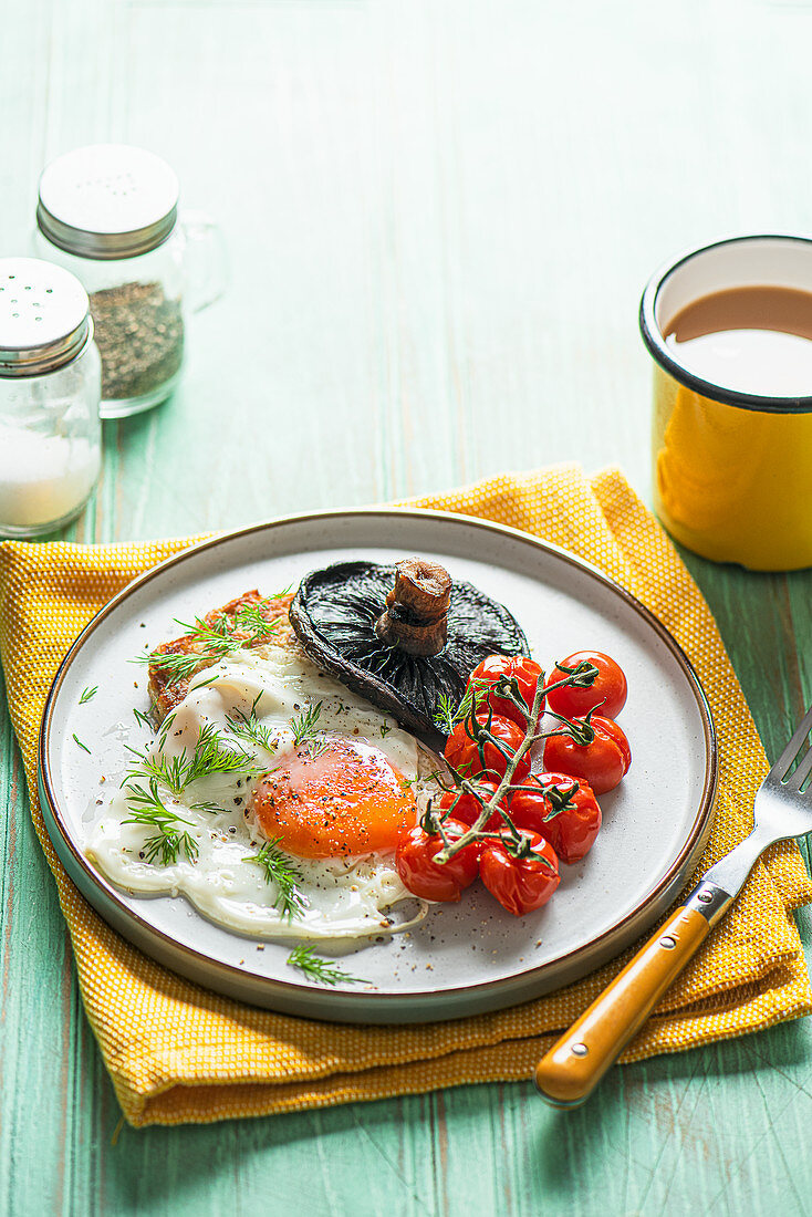 Vegetarisches Frühstück mit Kartoffel-Pancake, Spiegelei, gegrilltem Pilz und Tomaten