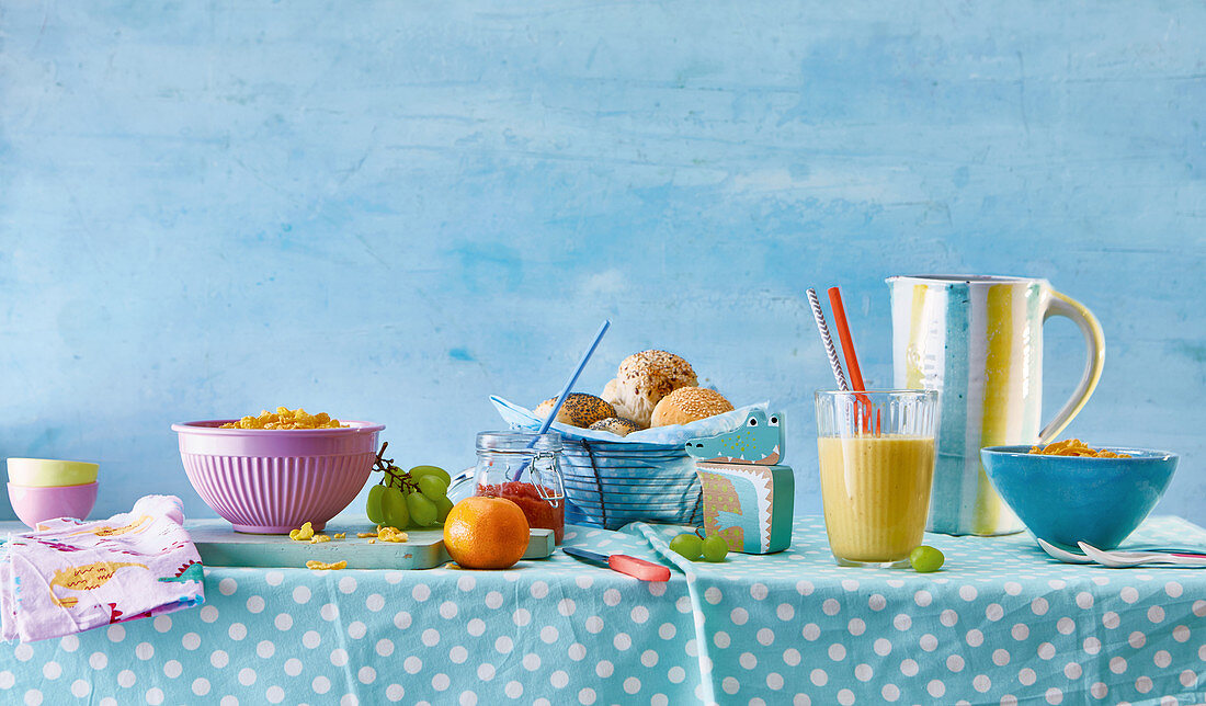 Frühstückstisch mit Brötchen, Saft, Müsli und Obst für Kinder