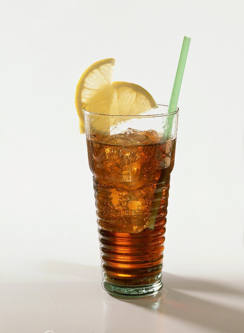 Cuba libre in tall glass with lemon slices and straw