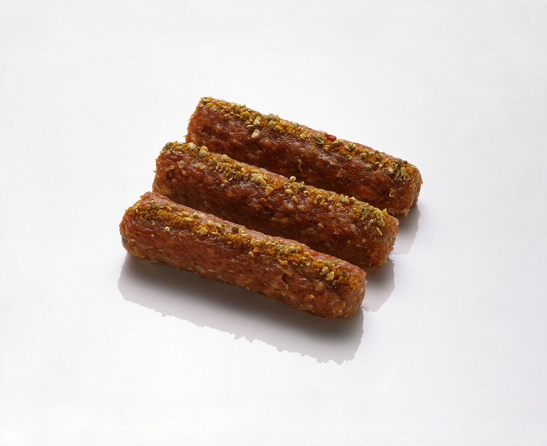 Three raw mince rolls sprinkled with spices