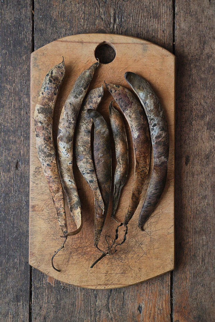 Dried bean pods on a rustic wooden board
