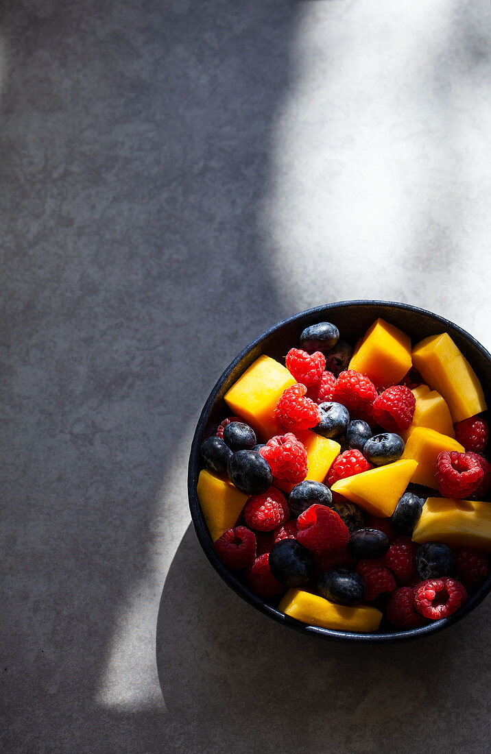 Colourful fruit salad with pieces of mango, raspberries and blueberries
