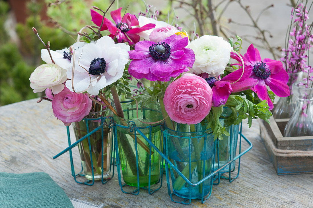 Anemones and ranunculus in glasses in a carrier