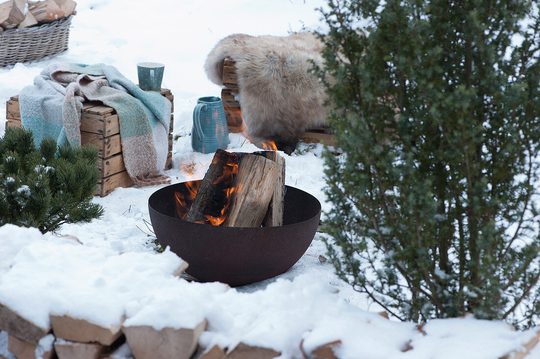 Firepit with firewood, wine crates with blankets and fur to sit on