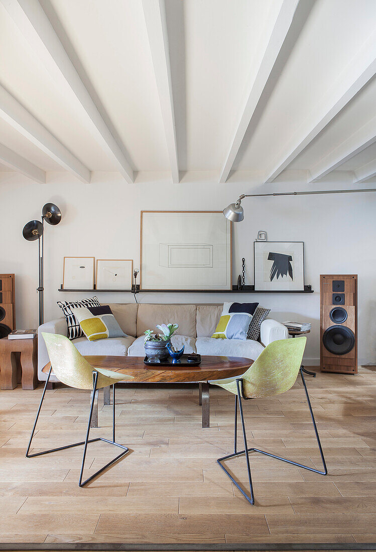 Couchtisch mit Holzplatte und filigrane Stühle vor Sofa in Loft-Wohnung