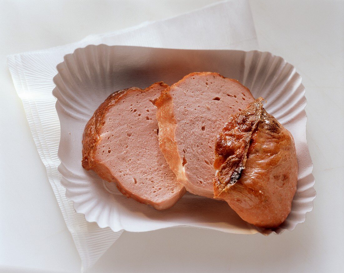 Three slices of warm liver cheese (meatloaf) on paper dish