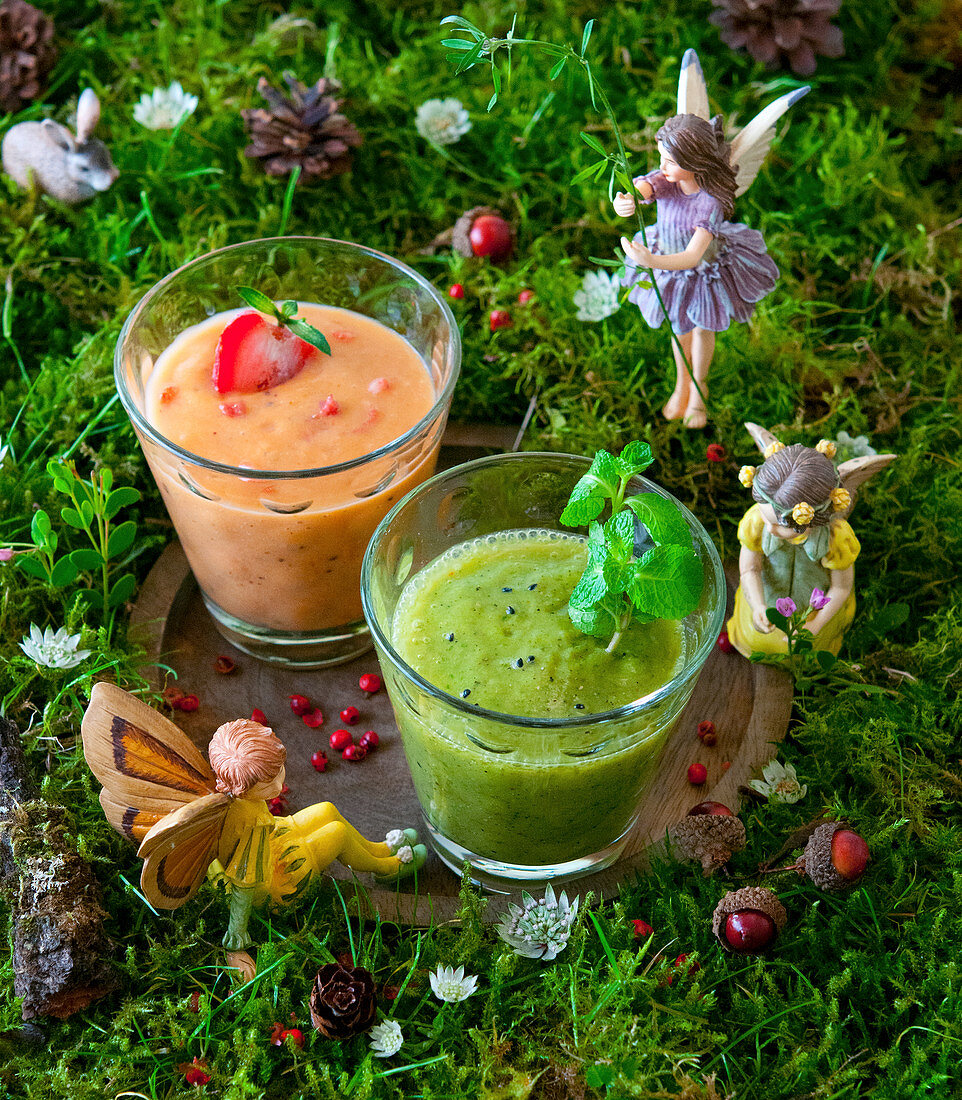 A kiwi smoothie and a strawberry smoothie in a fairy field
