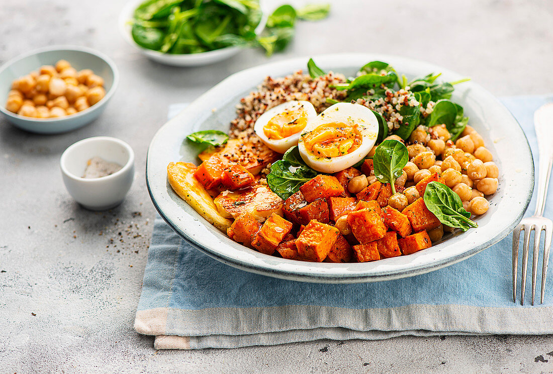 Quinoa-Bowl mit Süßkartoffeln, Kichererbsen, Spinat und gekochtem Ei