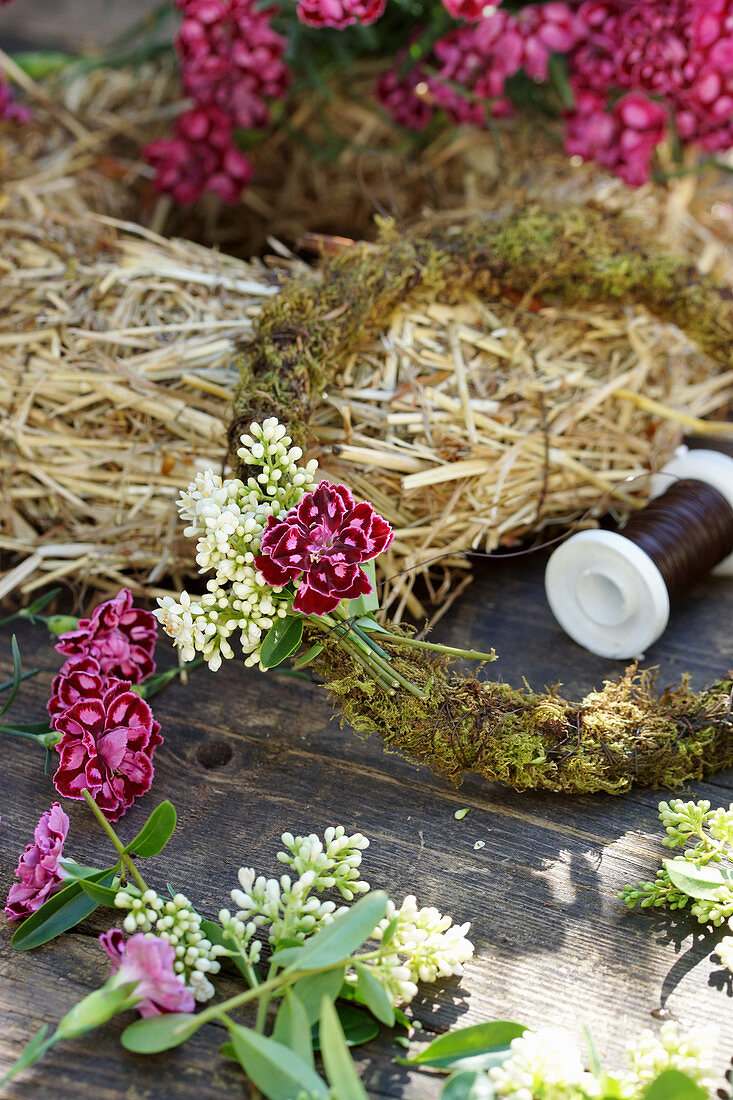 Tying a wreath of privet flowers and carnations