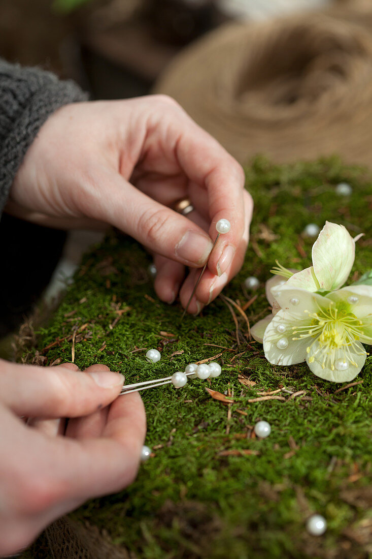 Stick pins with white flowers in the plug-in compound with moss