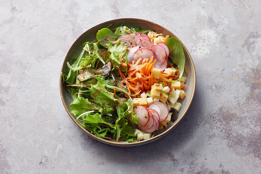 A salad with radishes, grated carrot, cheese and a nut mousse dressing