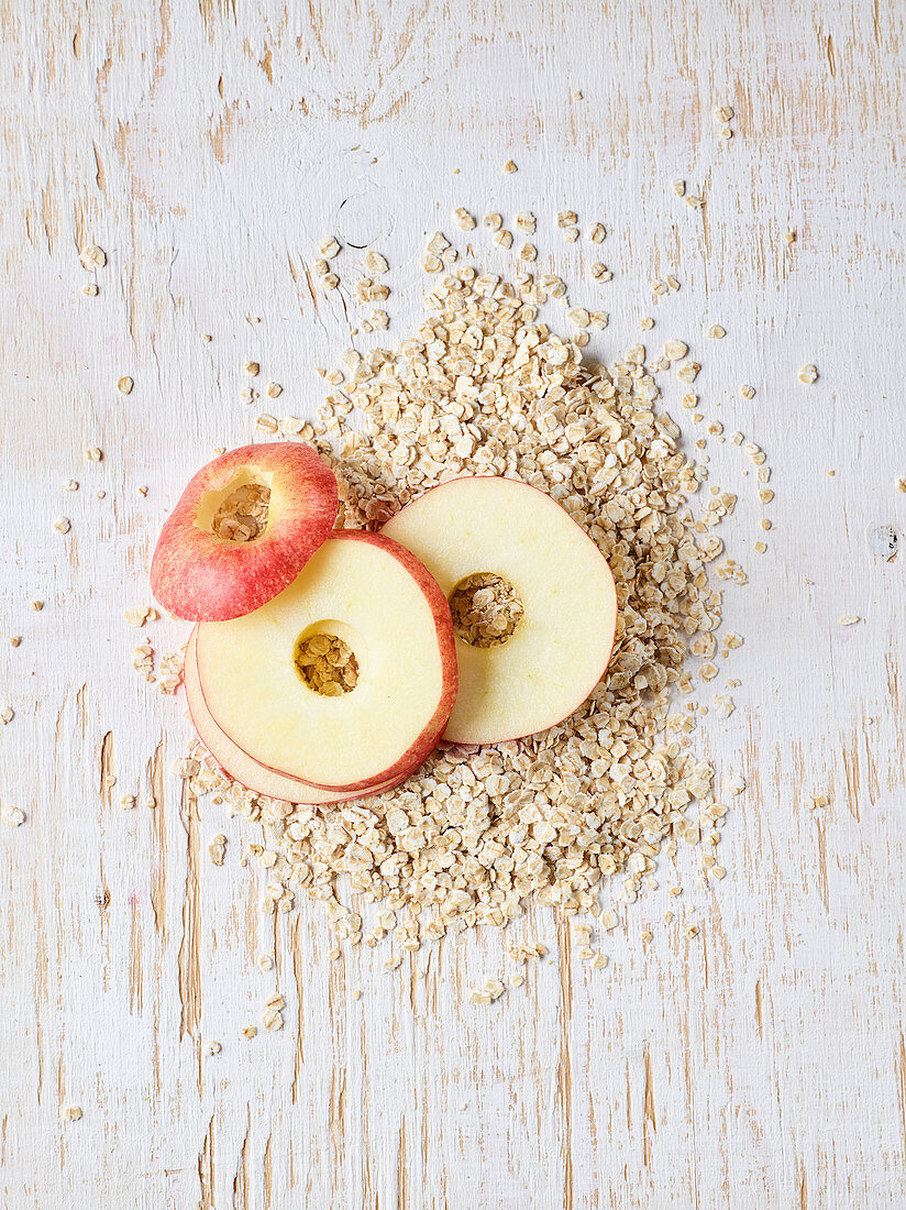Raw apple rings and oats on a wooden surface