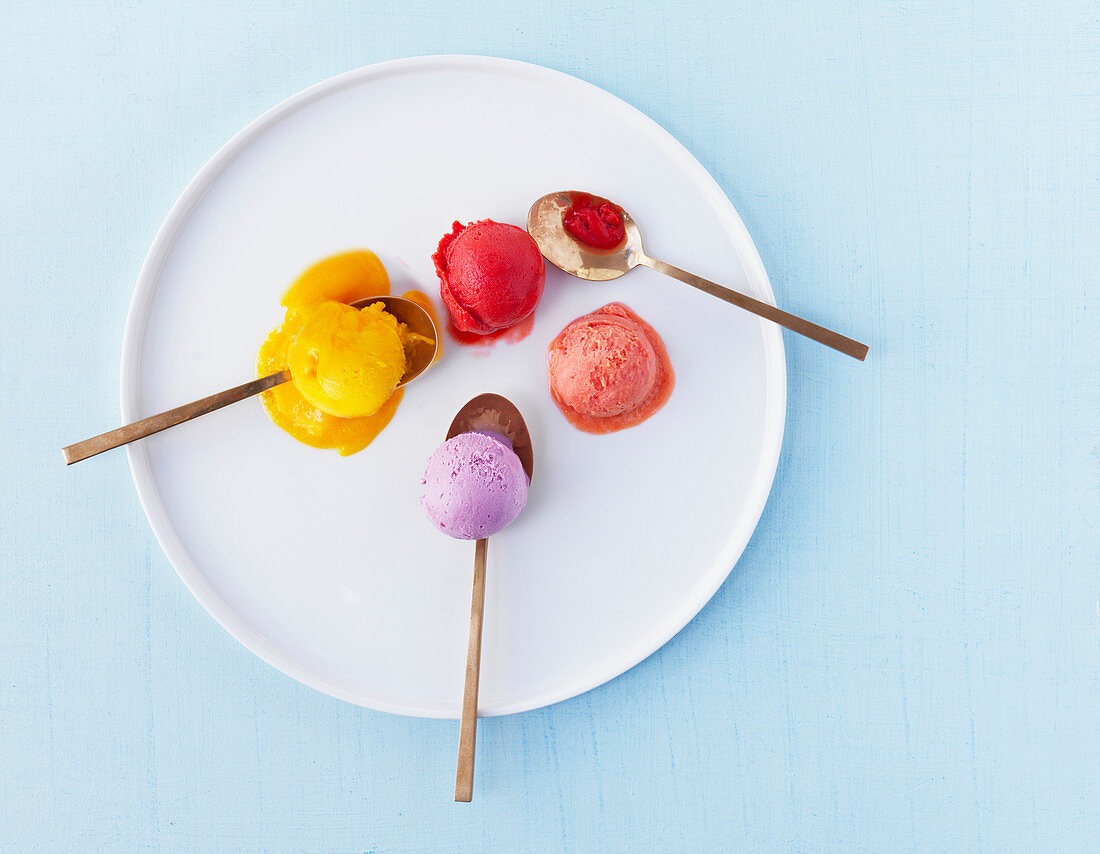 Verschiedene bunte Eiskugeln mit Löffeln auf Teller