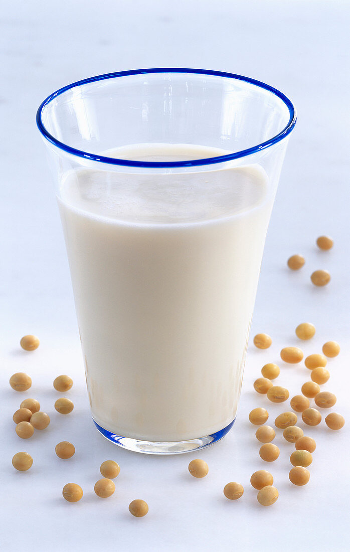 A glass of soy milk surrounded by soybeans