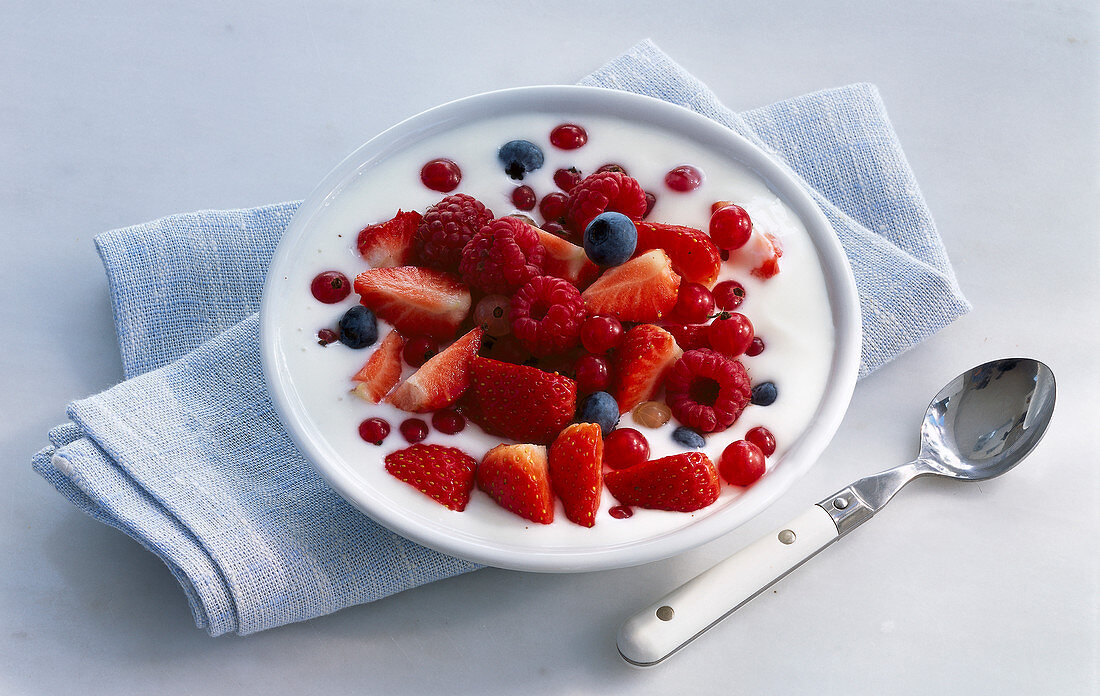 A bowl of yogurt with lots of red berries