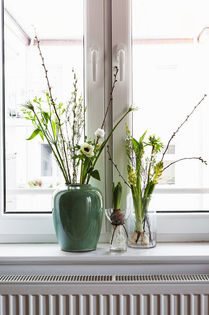 Vases of white spring flowers: tulip, anemone, willow catkins, waxflower, hyacinths, star-of-Bethlehem and cherry branch