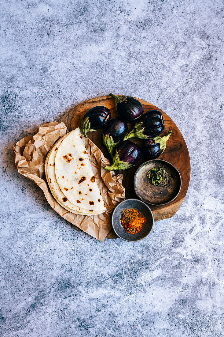 Baby-Auberginen, gemahlene Gewürze und Roti als Zutaten für indisches Curry