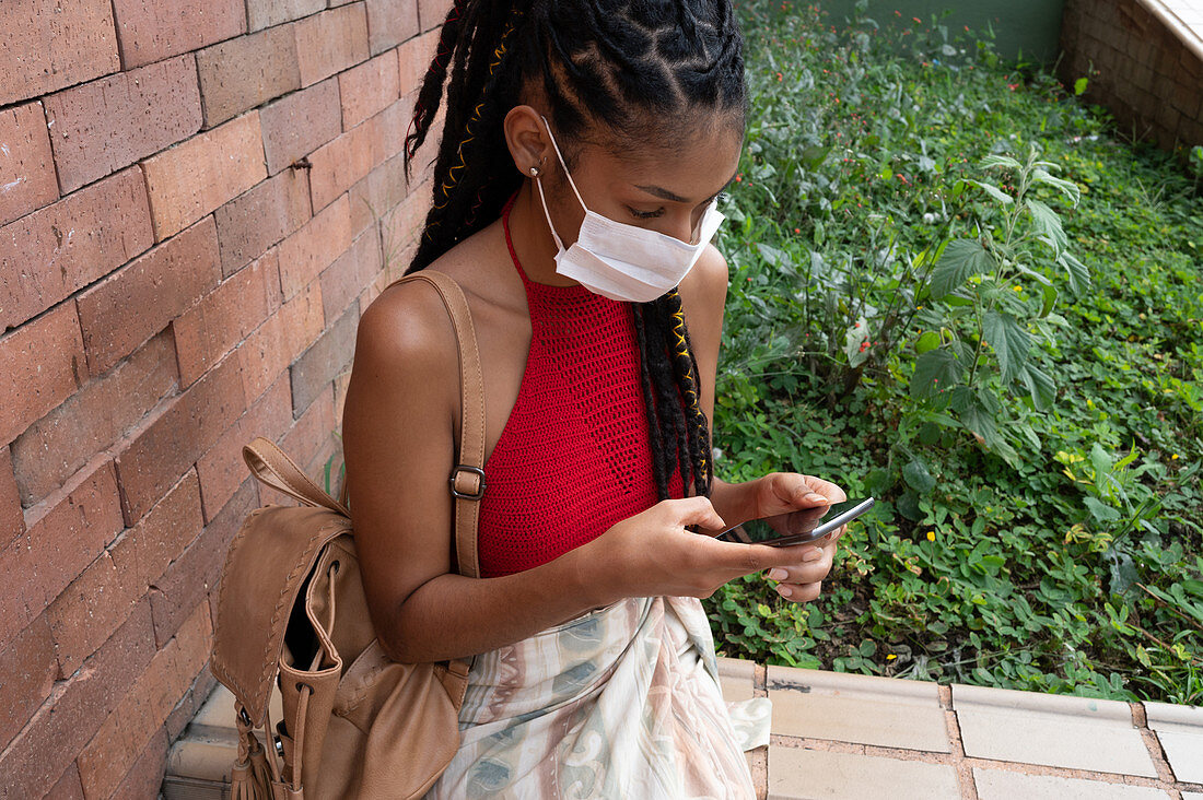 Young woman in facemask using smartphone