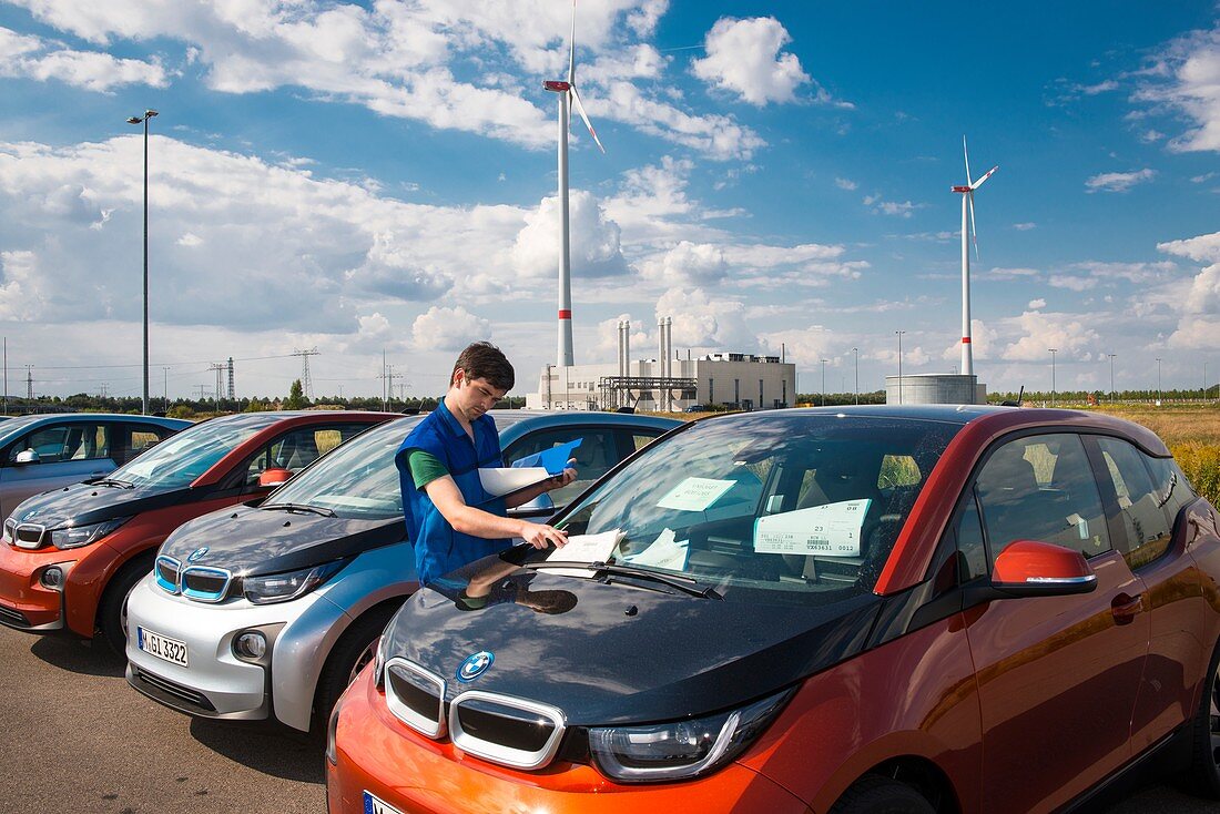 Worker checking finished cars at a car factory, Germany