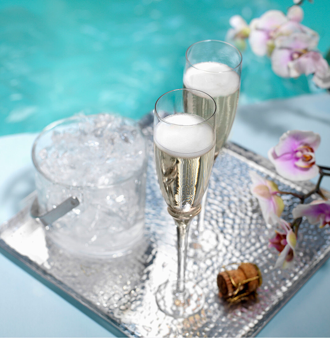 Champagner am Pool in zwei Flöten auf Silbertablett mit Eiskübel