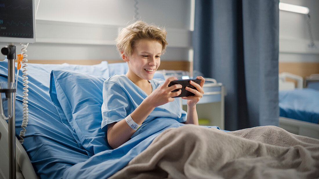 Boy using smartphone in hospital bed