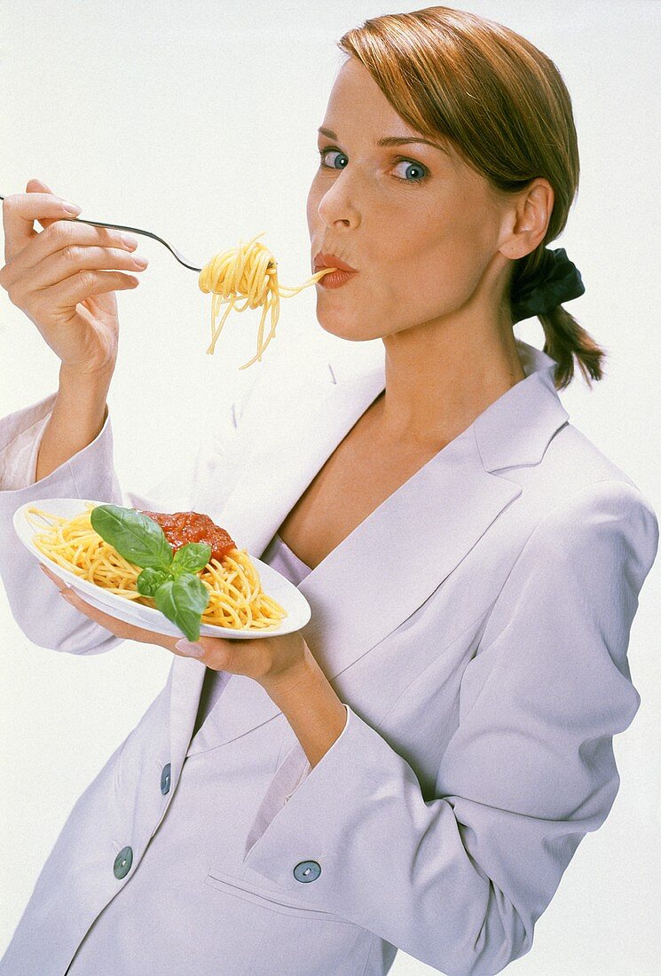 Young woman eating spaghetti with tomato sauce