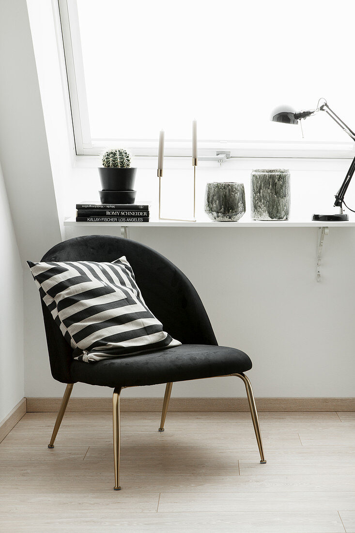 Black easy chair with black-and-white scatter cushion next to window
