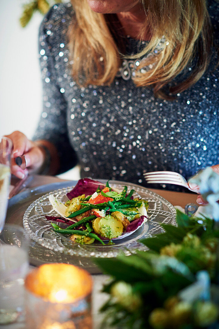 Frau isst festlichen Hummersalat mit Kartoffeln, Bohnen und Radicchio