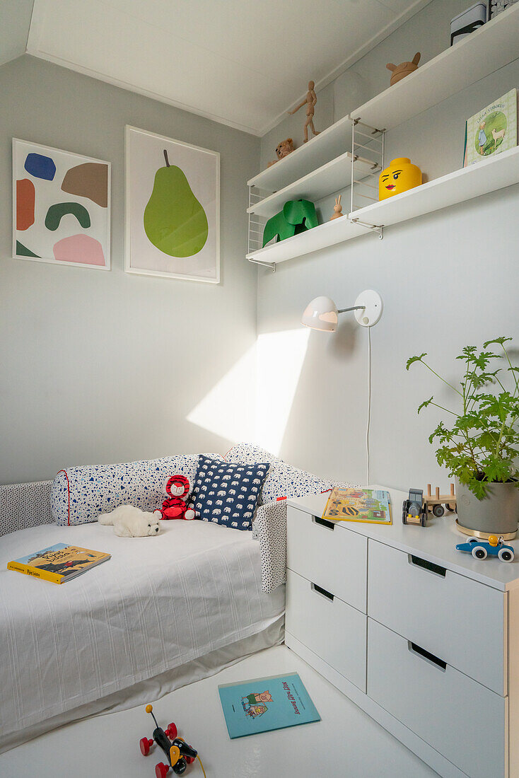 Helles Kinderzimmer mit Bett, Schubladenschrank und Regalen